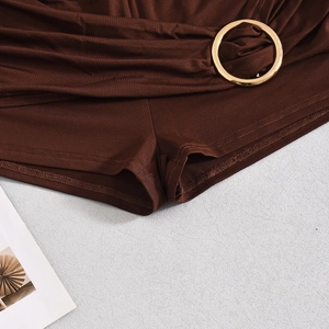 Detailed macro view of dark brown shorts showing premium stitching and gold metal buckles