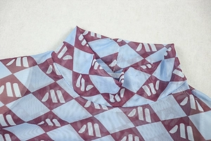 Detail of high neck mesh dress featuring tricolor Harlequin print and sheer texture