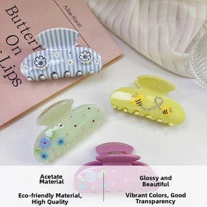 Detail of acetate hair claws featuring bee and flower designs with sparkling rhinestones