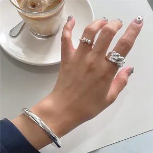 Close-up of polished silver bow ring and textured ring set in a lifestyle scene