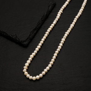 Detailed close-up of natural freshwater pearls on a textured black stone background