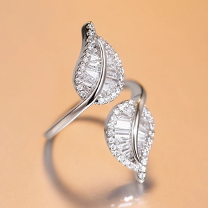 Macro shot of silver leaf ring with sparkling cubic zirconia on warm beige background