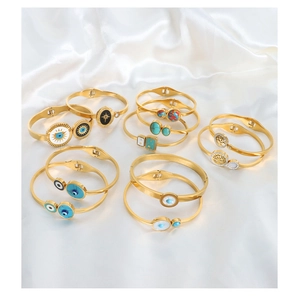 Collection of golden evil eye and tree of life bangles on white silk background