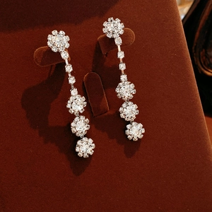 Detailed macro view of silver flower tassel earrings with zircons on a velvet jewelry stand