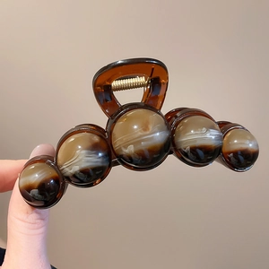 Detailed macro view of amber resin hair claw clip with sphere marbled texture