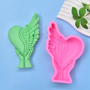 Silicone mold for DIY heart with wings held by hands and finished green soap sample