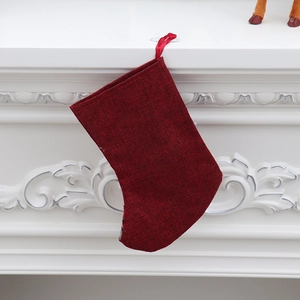 Classic red Christmas stocking made of textured linen hanging on a white fireplace mantle