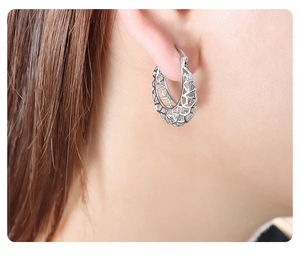Detail view of silver hollow U-shaped geometric earrings worn on an earlobe