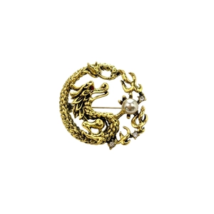 Macro detail of vintage dragon brooch with bronze finish, pearl, and red gemstone eye