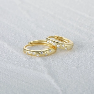 Detailed view of gold plated flower zircon hoop earrings on a grey stone surface