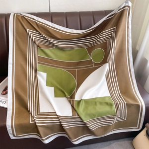 Detailed close-up of patterned square scarf draped on leather, showing luxury silk texture