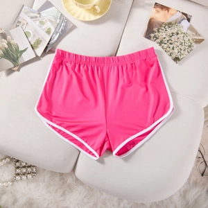 Detailed flat lay of rose red sports shorts with white piping on a cozy home background