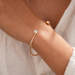 Nahaufnahme des goldenen geometrischen Armreifs mit funkelnden Strasssteinen am Handgelenk