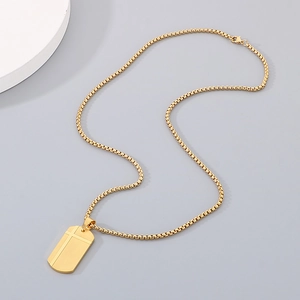 Detail of a gold stainless steel dog tag pendant with minimalist cross groove on box chain