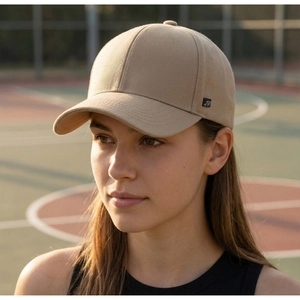 Khaki cotton baseball cap with black square woven logo on side worn by model outdoors