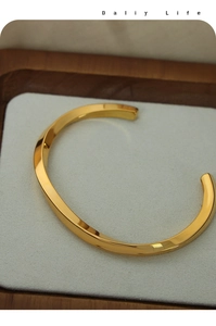 Close-up of gold-plated titanium steel cuff bracelet with elegant twisted Mobius design