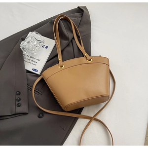 Detailed top view of a khaki tote bag on a grey blazer with golden metal accents