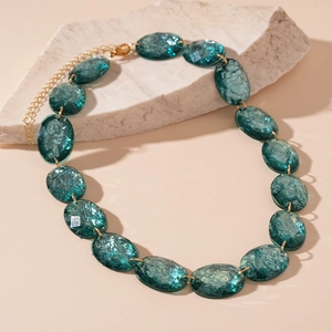 Vintage oval teal resin necklace with gold metal rings on natural stone background