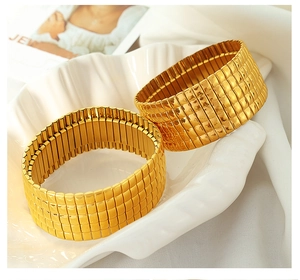 Detailaufnahme eines breiten goldenen Armbands mit Karomuster auf einem Display