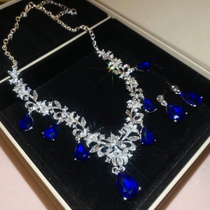 Macro detail of royal style jewelry set with blue teardrop gems in a black gift box