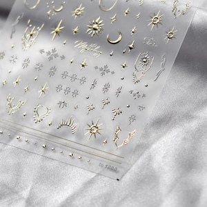 Gold metallic sun and moon mythology nail art stickers on silver silk fabric background