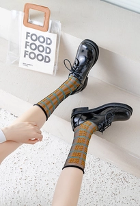 Detail of black patent leather derby shoes paired with geometric pattern mesh socks