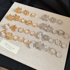 Detailed arrangement of gold and silver flower rings with pearls on a linen display board