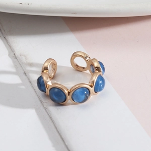 Détail de la bague ouverte dorée avec six pierres bleues rondes au fini œil de chat