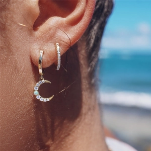 Close-up of gold moon hoop earrings with pavé zircons and opal stone on female model