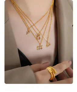 Close-up of layered gold zodiac necklaces with sparkling rhinestones and rope ring