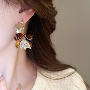 Gros plan d'une boucle d'oreille fleurie avec nœud, pendentif en résine et perles
