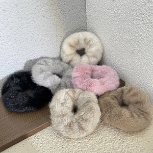 Set of 6 plush faux fur scrunchies in neutral colors on a minimalist wooden background