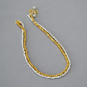 Close-up of double-layered gold and silver faceted metal bead necklace with extension chain