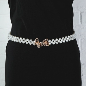 Close-up of a double-row pearl waist chain featuring a gold rhinestone butterfly buckle