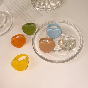 Gros plan sur des bagues colorées en résine en forme de cœur sur un plateau en verre chic