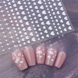 Detail of white heart and star nail art stickers on pink glitter nails