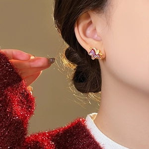 Detail view of a red enamel pony earring with sparkling zircon on a woman's ear