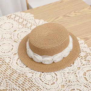 Detailopname van een beige strohoed versierd met elegante witte kanten roosdecoraties
