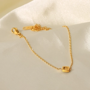 Elegantes 18K vergoldetes Edelstahl-Armband mit quadratischem Anhänger auf weißer Seide