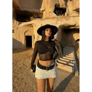 Detail of black sheer mesh long sleeve top featuring a chic twist knot front design