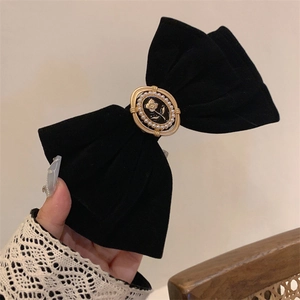 Close-up of black velvet bow hair clip with vintage rose relief and faux pearl detail