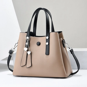 Sac à main marron clair en cuir PU avec anses noires et pendentif cœur sur fond blanc