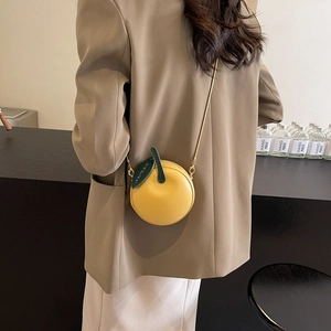 Cute lemon shaped crossbody bag in bright yellow leather with green leaf and metal chain