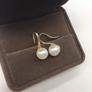 Close-up of elegant white freshwater pearls with golden hooks on brown velvet
