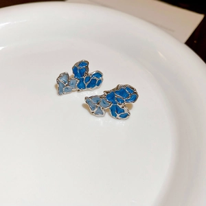 Macro des boucles d'oreilles émaillées bleues avec bordure géométrique en argent