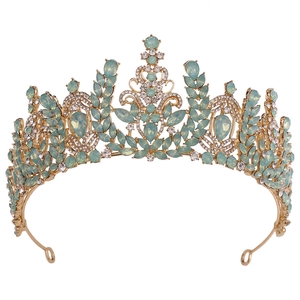 Detailed close-up of a gold bridal crown with green crystals and sparkling white rhinestones
