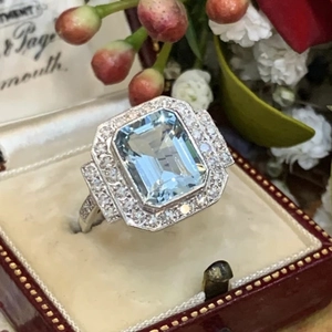 Macro shot of an Art Deco emerald-cut blue gemstone ring in a vintage red gift box