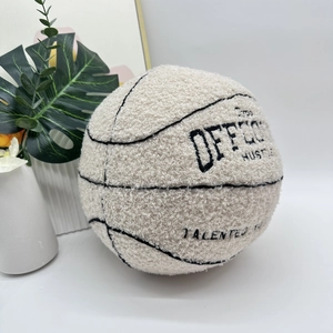 Detail of cream sherpa basketball pillow with black embroidery in a minimalist setting