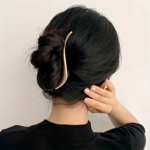 Macro shot of 13.2cm golden S-curved metal hair clip worn on a bun hairstyle