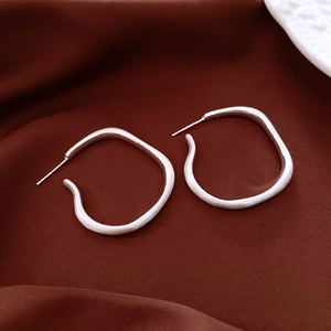 Detailed macro view of silver irregular geometric earrings on vintage silk background